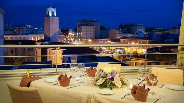 A dining table set for two with a city view, including a tower and buildings.
