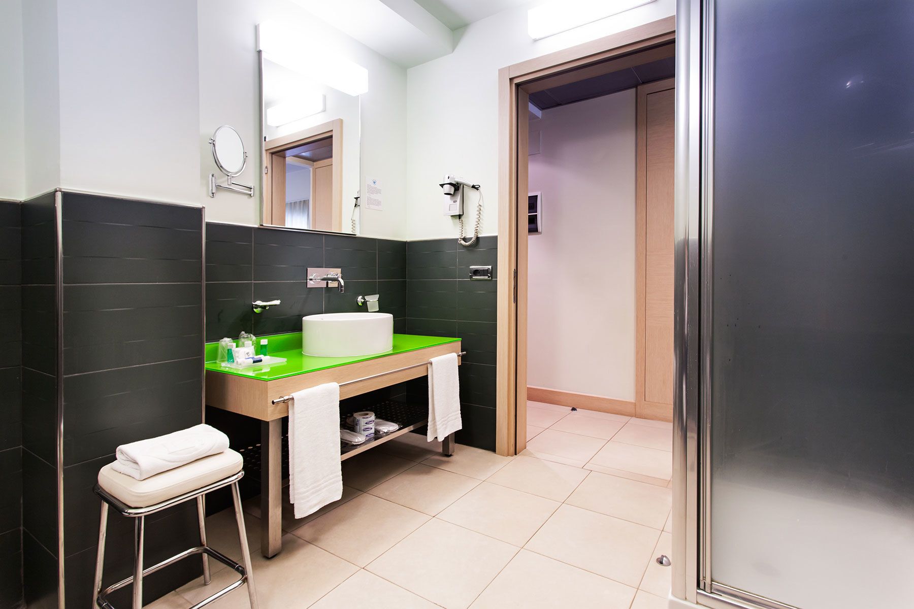Ein modernes Badezimmer mit einem grünen Waschtisch, einer weißen Toilette und einer Duschkabine aus Glas.