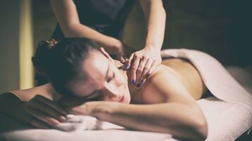 A person receiving a massage in a dimly lit room.