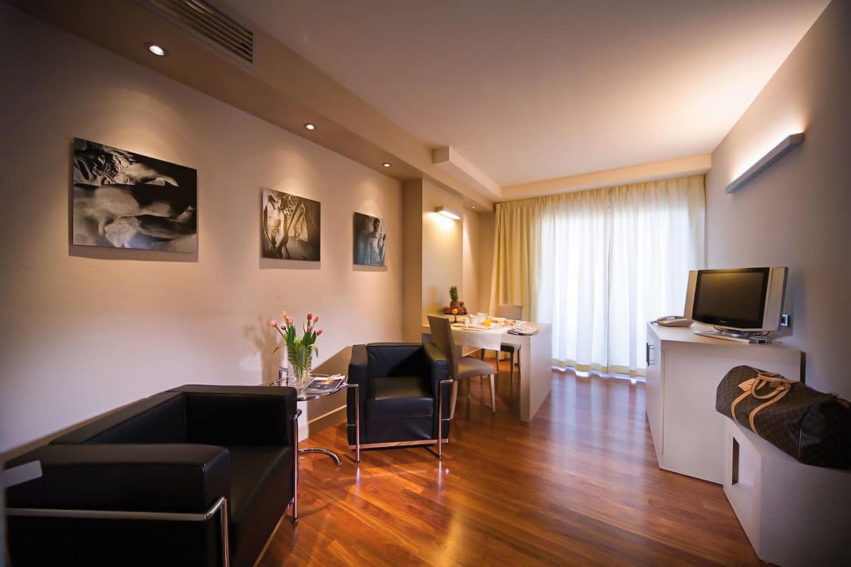 Ein modernes Hotelzimmer mit Essbereich, Fernseher und Kunstwerken an den Wänden.