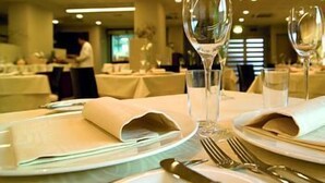 A dining table set with white tablecloths, folded napkins, and clear wine glasses with flowers.