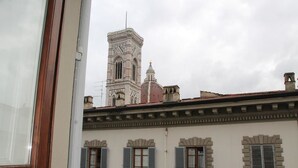 Un edificio con una torre destacada y numerosas ventanas con contraventanas.