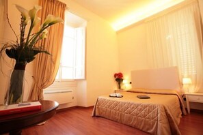 A hotel room with a bed, bedside table, lamp, and a vase with flowers. - B&B Magnifico Messere (Florence)
