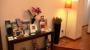 Un mostrador de recepción con folletos, un jarrón con flores y una lámpara.