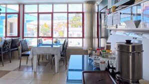 A dining area with a table and chairs, a coffee machine, and a window with a view of buildings. - Aspawa Hotel (Denizli)