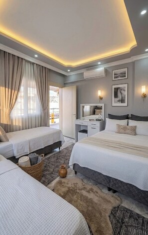 Una habitación de hotel moderna con dos camas, un escritorio y un ventanal con cortinas.