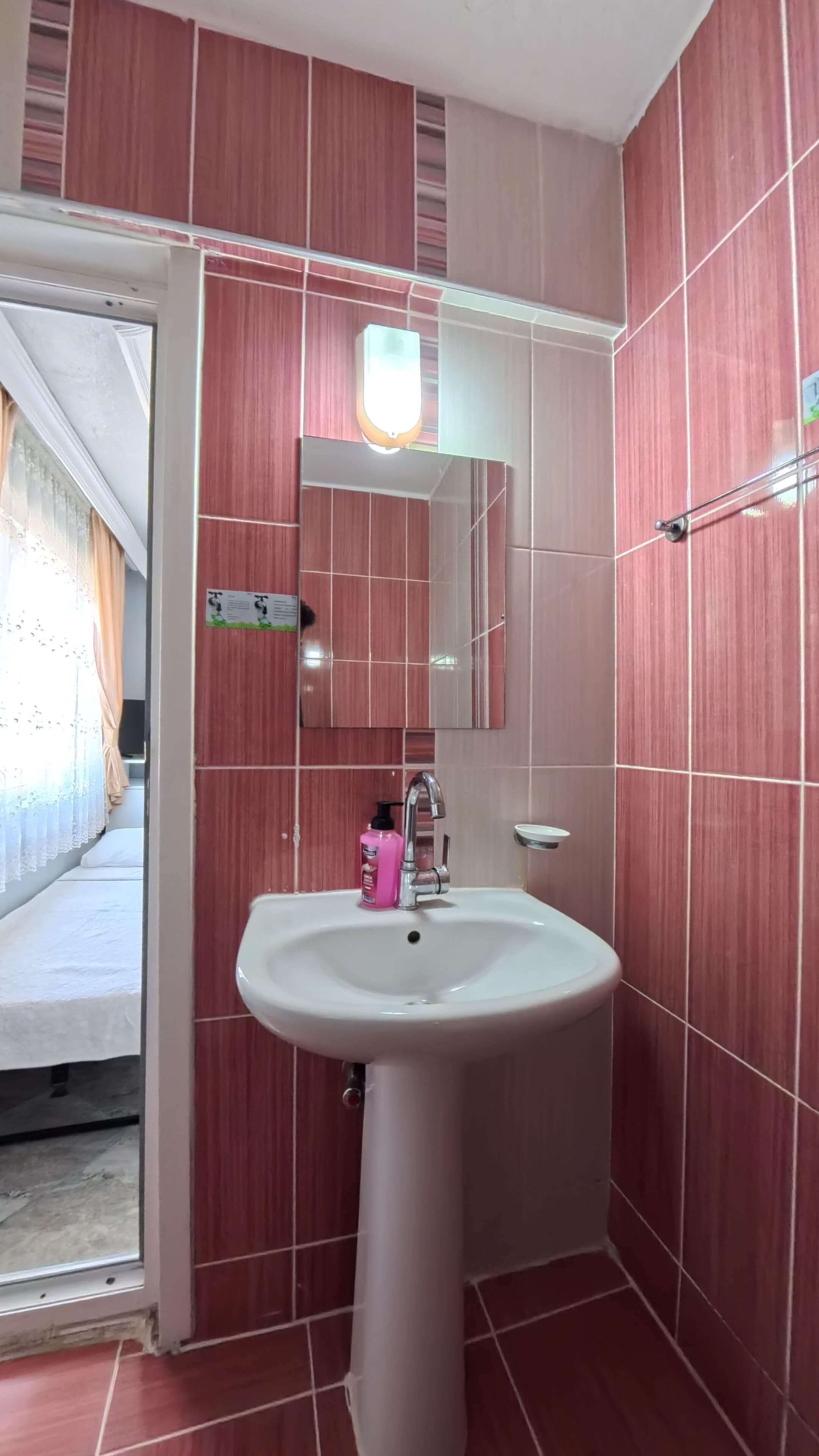 Un baño con lavamanos blanco, un espejo y una lámpara colgante arriba.