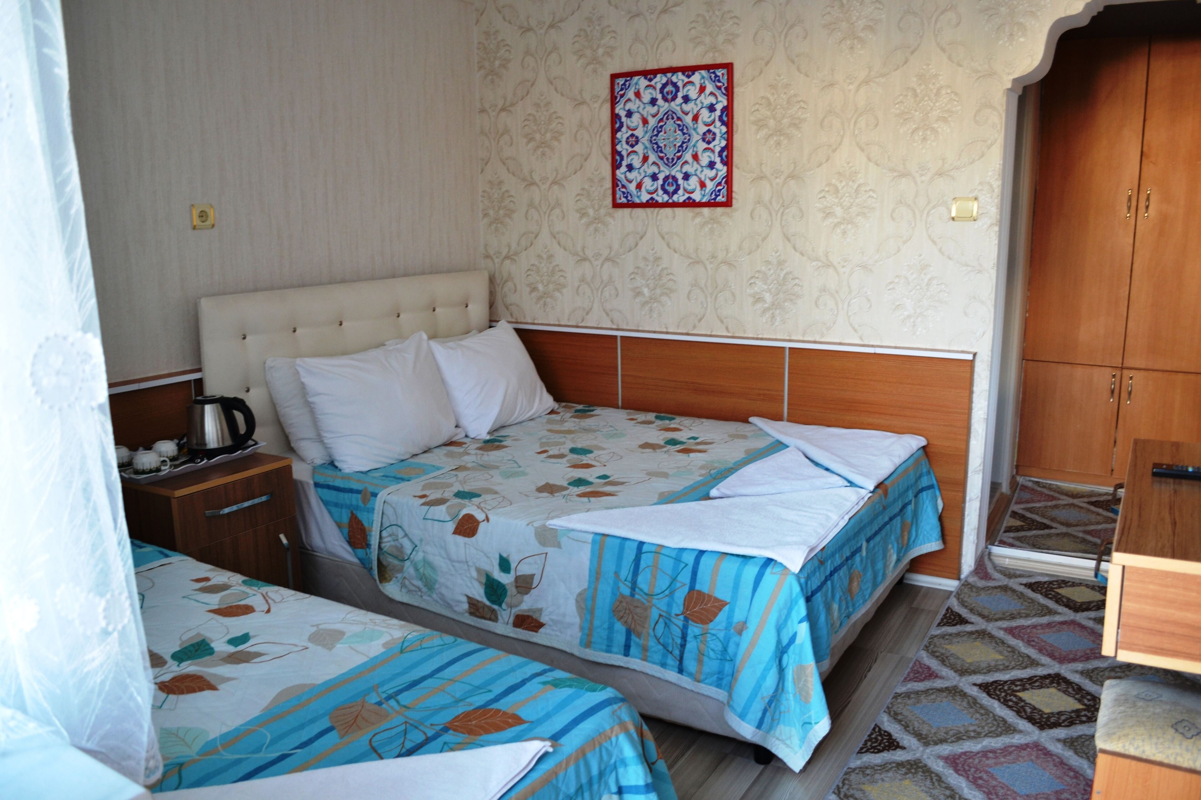 Una camera da letto con due letti, un'armadio in legno e una parete decorata.