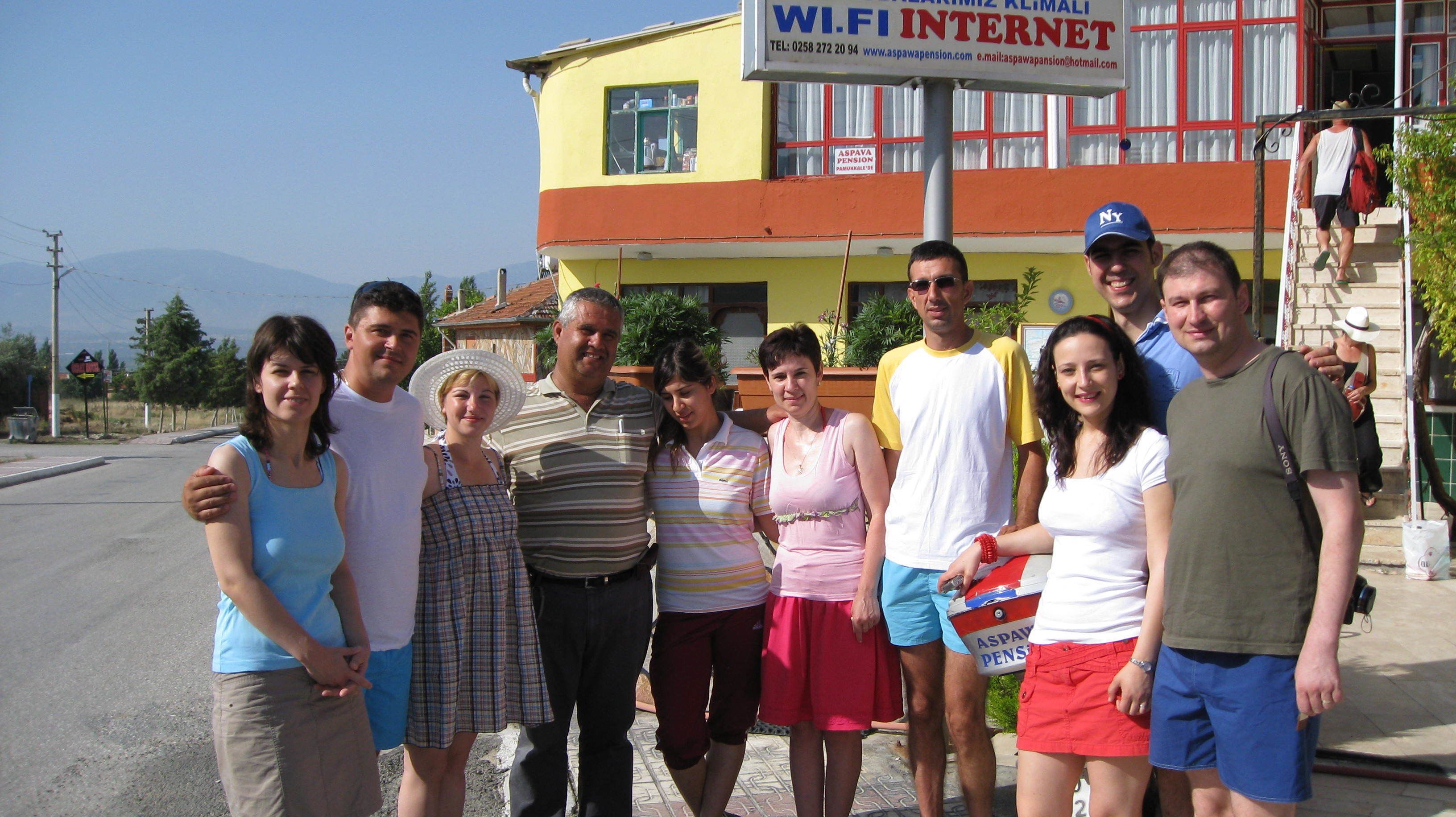 Un grupo de personas posando frente a un edificio con un letrero que anuncia servicios de internet WiFi.