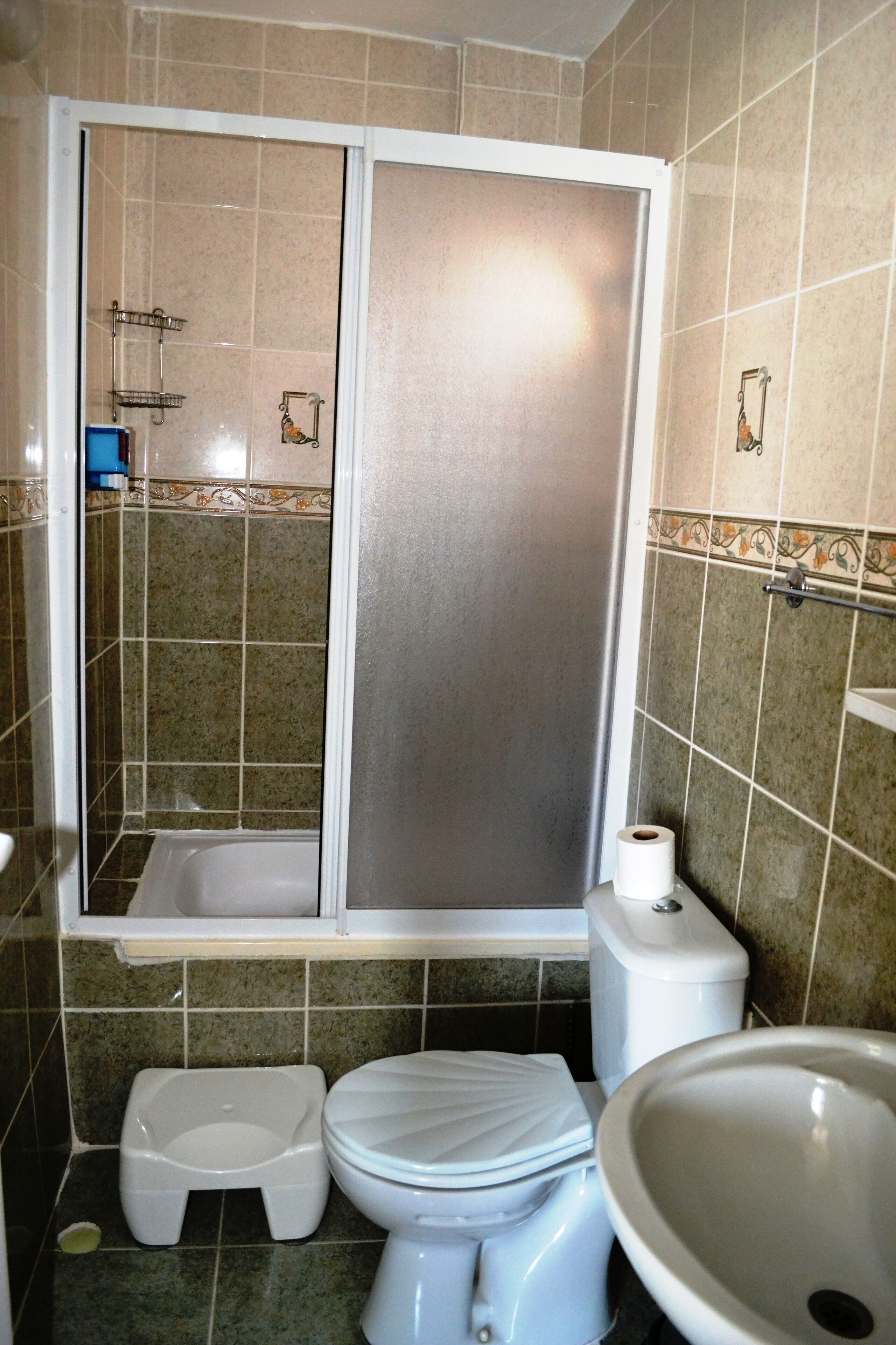 Un baño con cabina de ducha, inodoro y lavamanos.