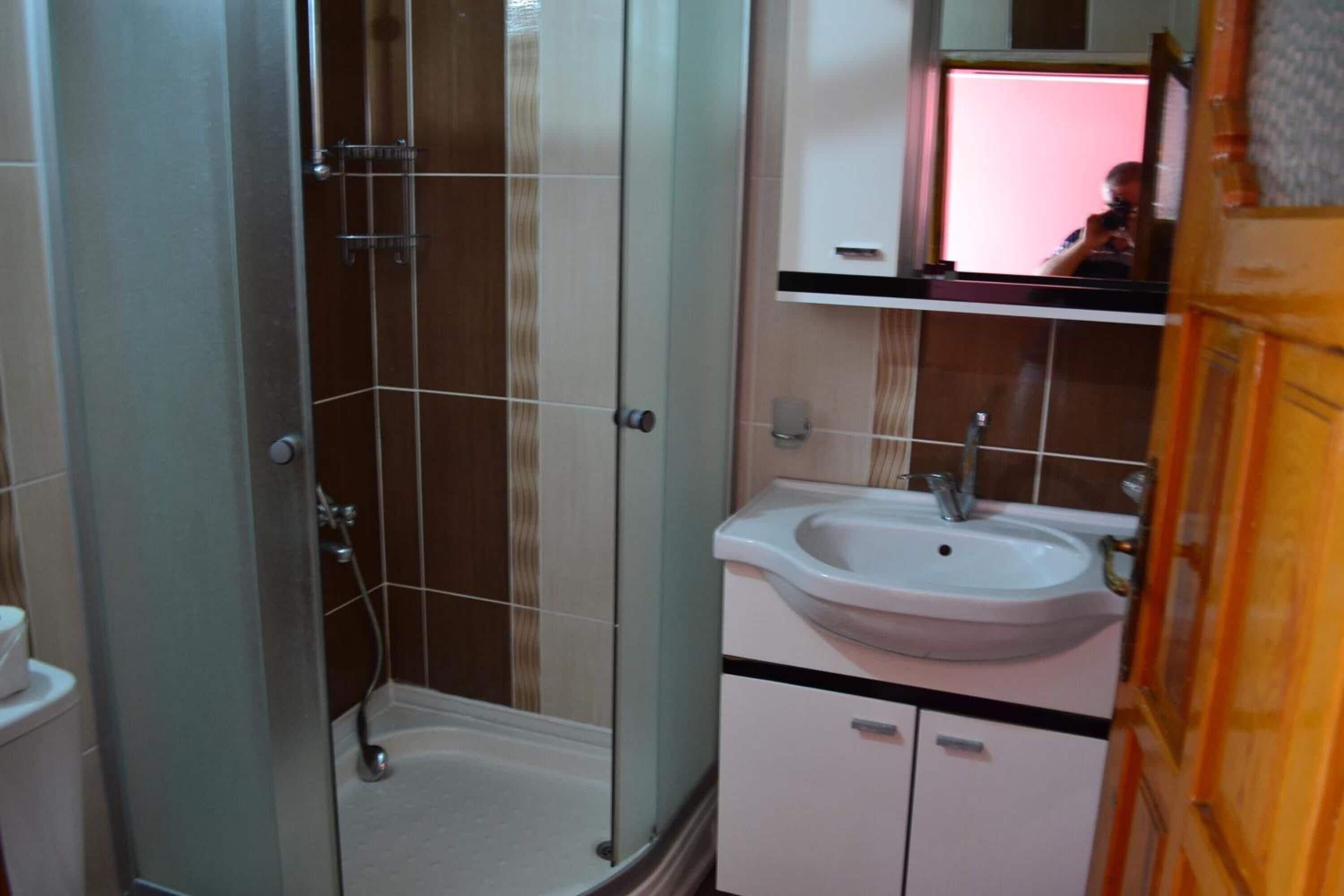 A bathroom with a glass shower enclosure, a white sink, and a mirror above the sink.