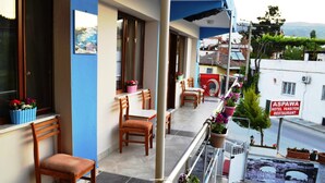 A balcony with wooden chairs and tables, potted plants, and a sign for ASPAWA HOTEL PANSIYON RESTAURANT. - Aspawa Hotel (Denizli)