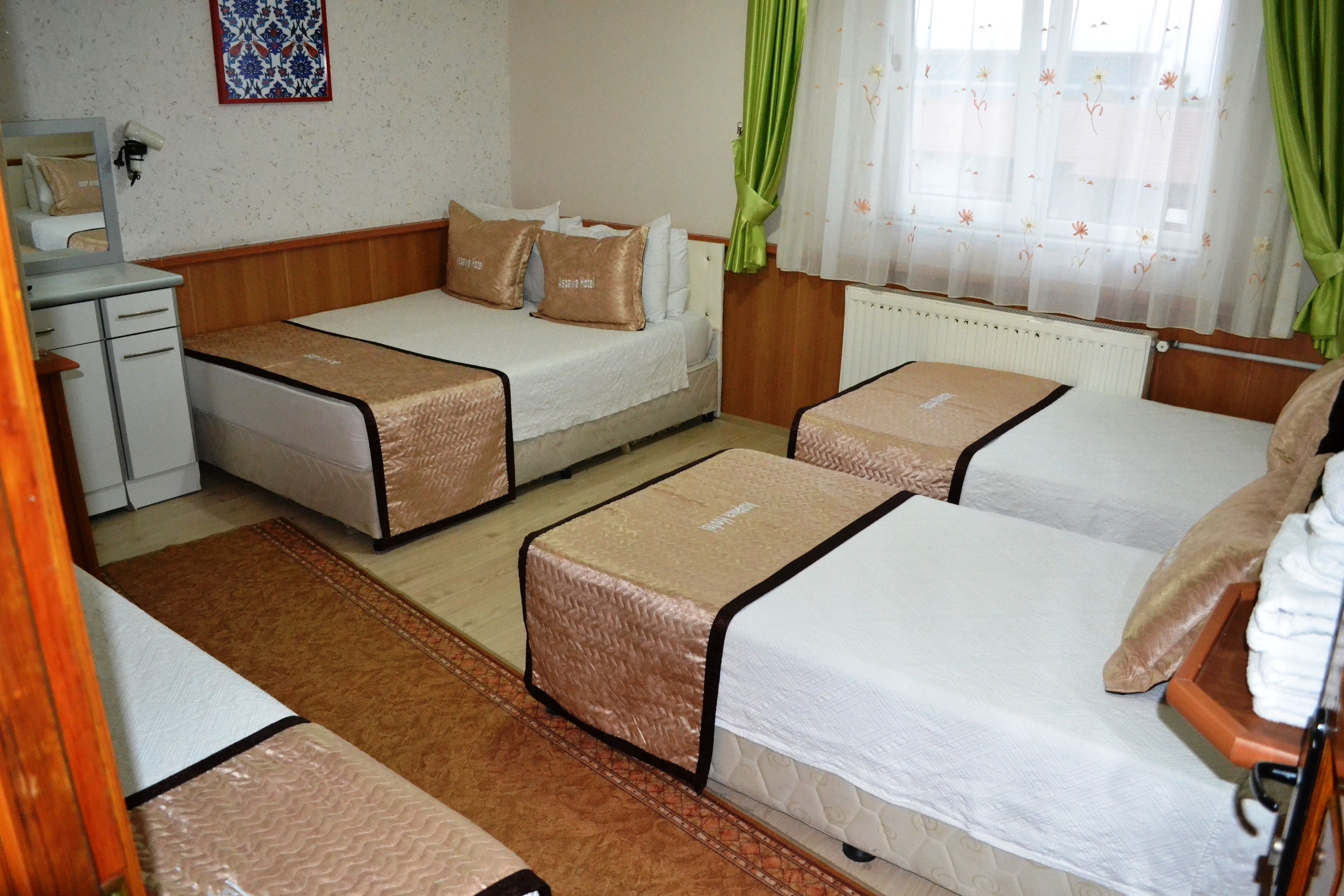 A hotel room with two single beds, a sofa bed, a desk, and a radiator.