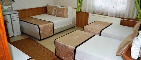 A hotel room with two single beds, a sofa bed, a desk, and a radiator.