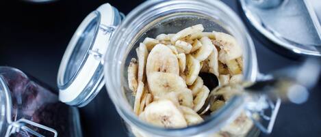 Un bocal en verre rempli de chips à la banane, dont le couvercle en métal est entrouvert.