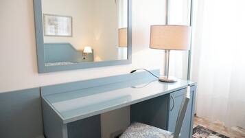 A modern bathroom with a vanity, a mirror, a lamp, and a patterned seat.