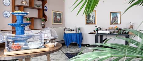 Une pièce aménagée avec un buffet, une table recouverte d’une nappe bleue et une étagère ornée d’objets décoratifs.