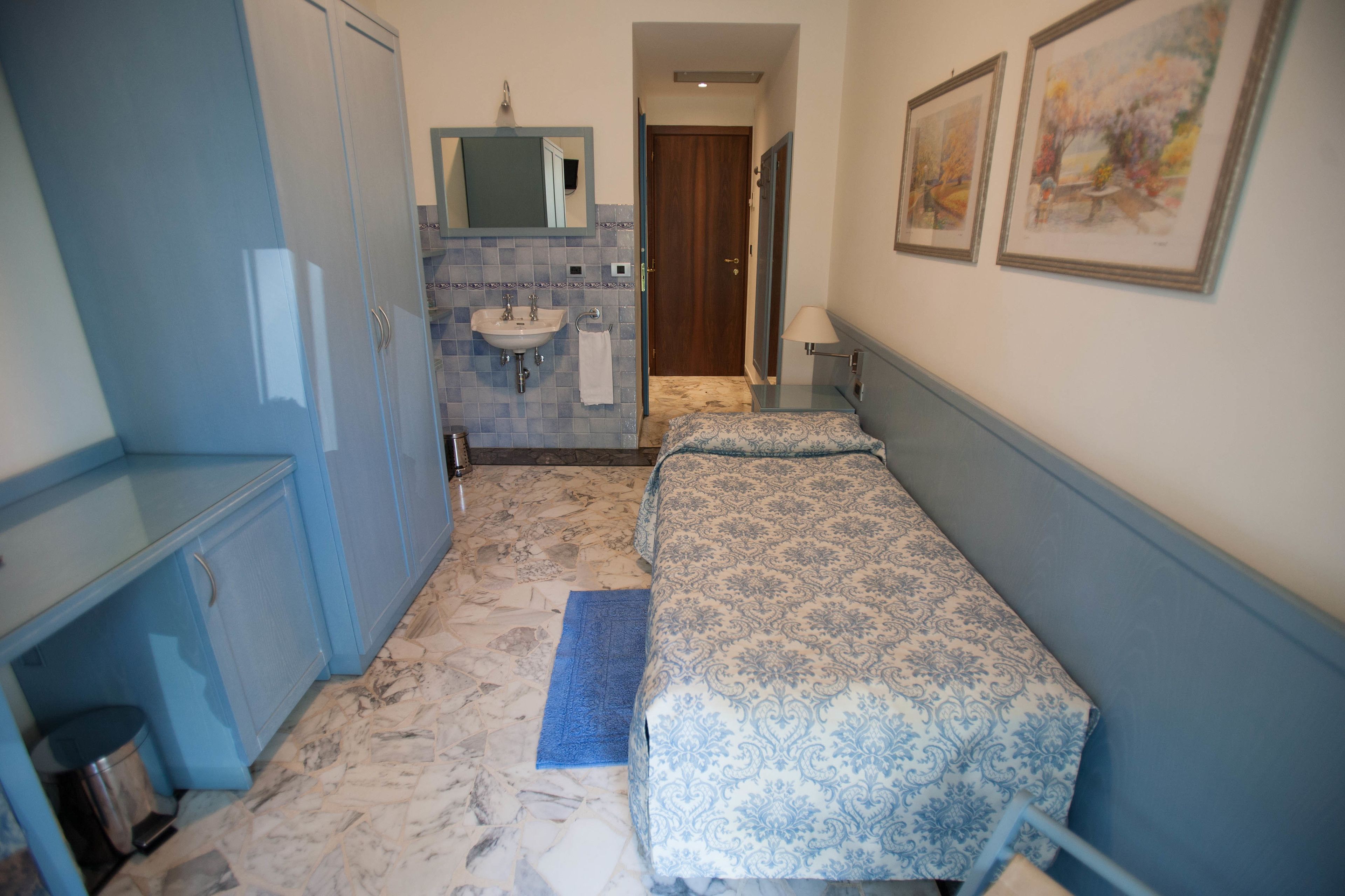 Une chambre à coucher comprenant un lit, une table de chevet, une commode, un miroir et une salle de bain avec un lavabo et des toilettes.