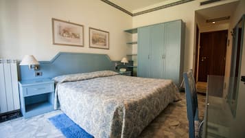 Een slaapkamer met een bed, nachtkastje, dressoir en een deur naar een andere kamer.