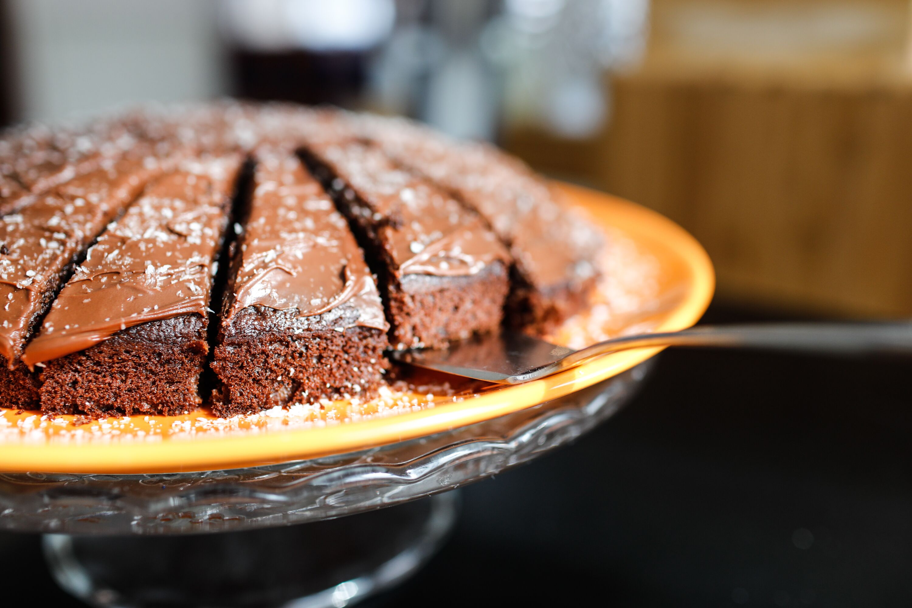 Un pastel de chocolate con una capa de caramelo sobre un expositor de vidrio.