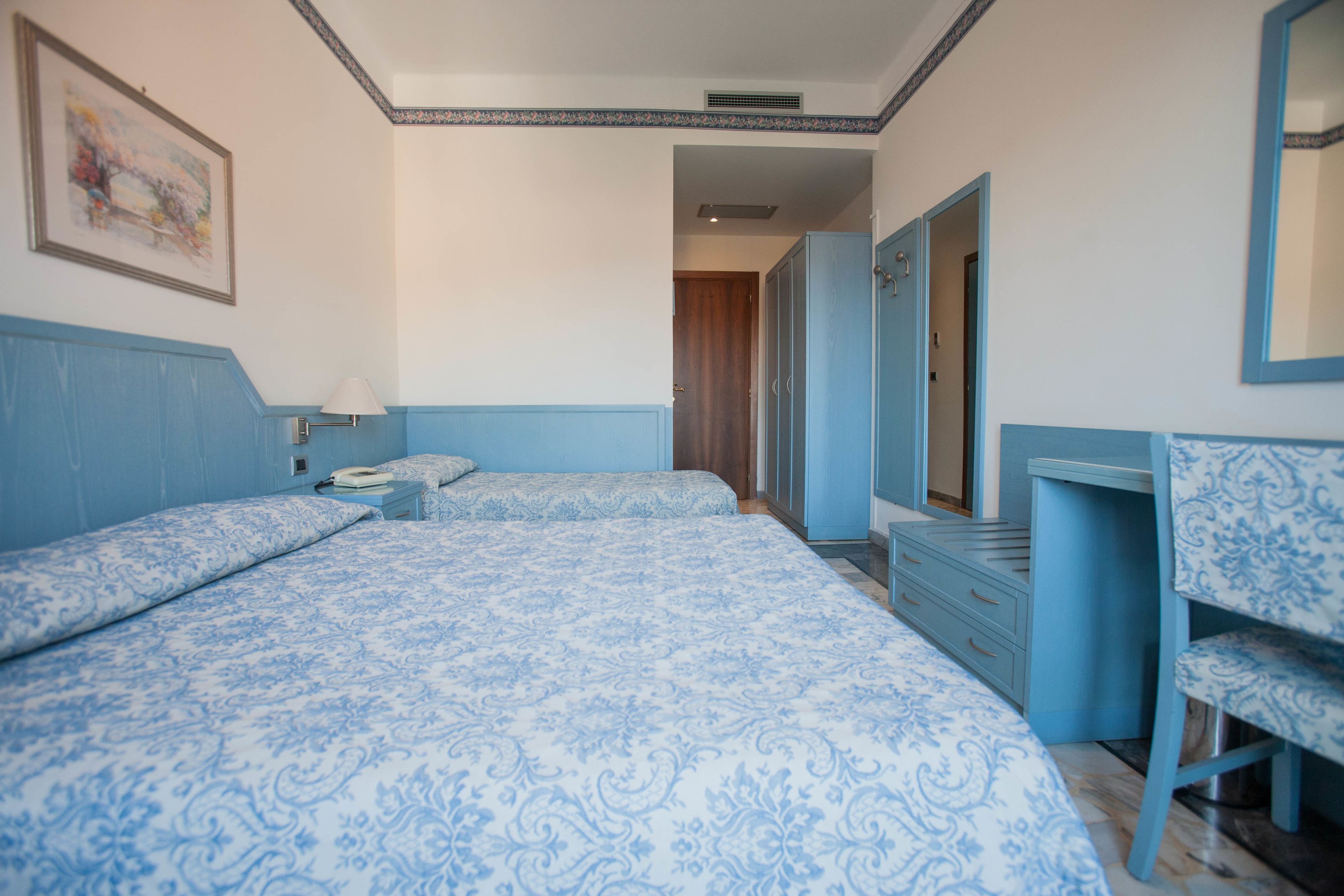 A bedroom with two beds, a dresser, a chair, and a mirror.