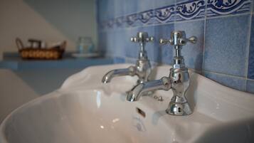 Un lavabo da bagno con due rubinetti e piastrelle decorative blu sullo sfondo.