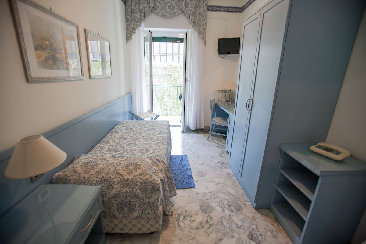 A bedroom with a bed, a desk, a wardrobe, and a TV.