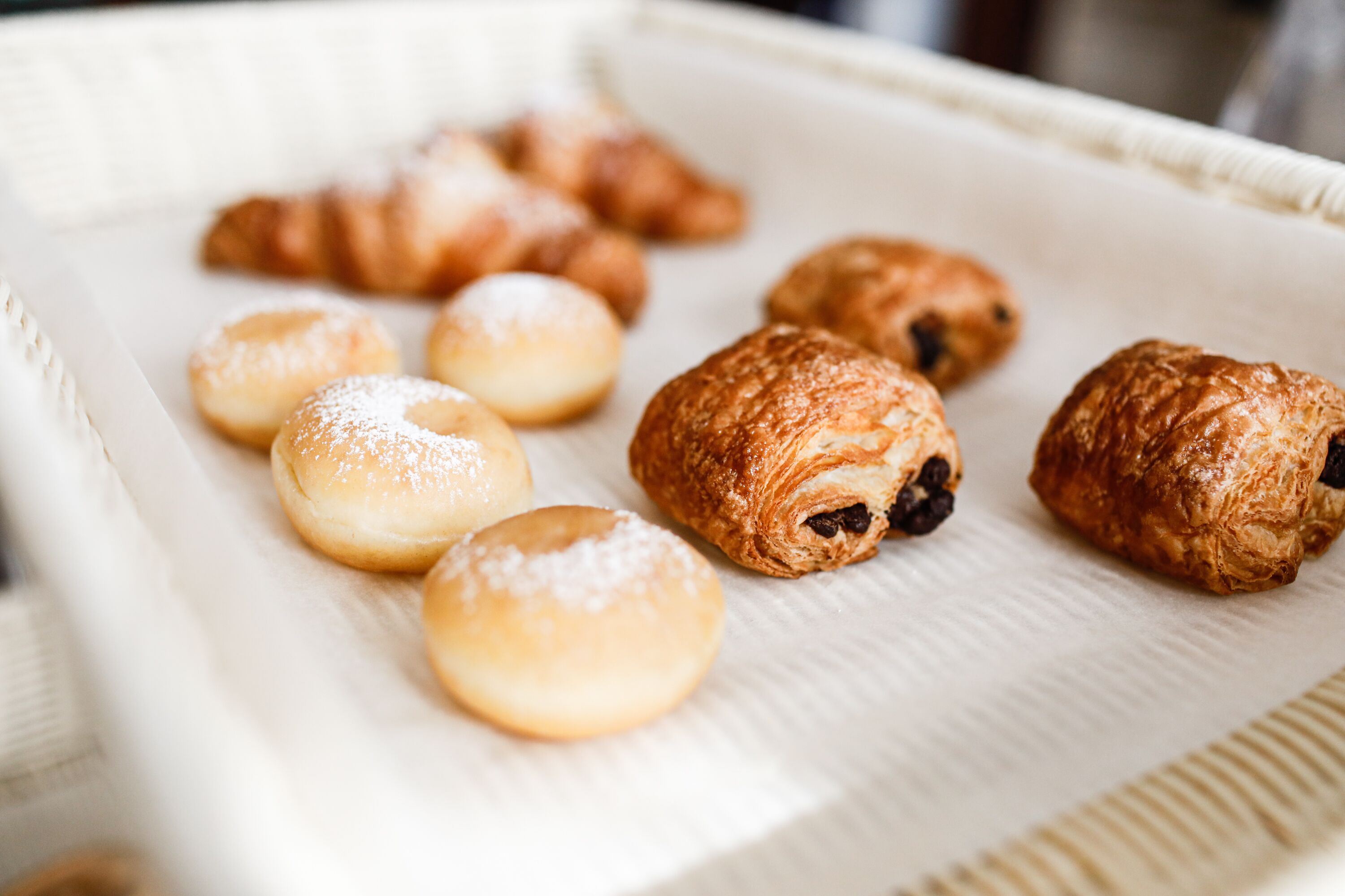 Een schaal met diverse gebakjes, waaronder croissants en donuts.