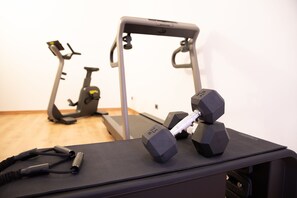 A gym with exercise equipment, including a treadmill and dumbbells on a mat. - Hotel Ariston (Imperia)