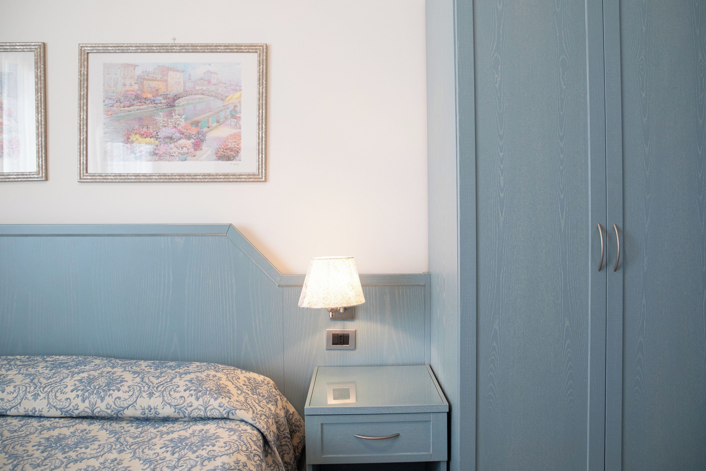 Ein Schlafzimmer mit einem Bett, einem Nachttisch mit Lampe, einer kleinen Schublade und einem Kleiderschrank.