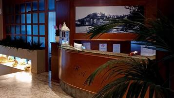 A reception area with a marble floor, a reception desk, a large window with a cityscape view, and a decorative lantern.