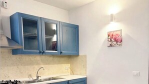 Een keuken met blauwe kastjes, een wit aanrecht, een gasfornuis en een eettafel met stoelen.