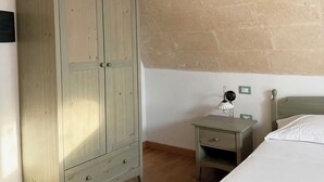 Une chambre avec une armoire en bois, une table de chevet avec une lampe et un lit.