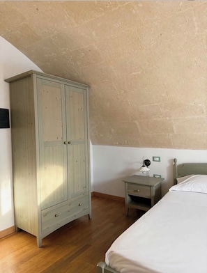 Ein Schlafzimmer mit einem Holzschrank, einem Nachttisch mit Lampe und einem Bett.