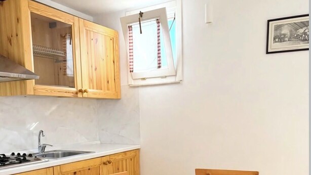 Une cuisine avec des meubles de rangement en bois, une cuisinière à gaz, un évier et une table à manger avec des chaises.