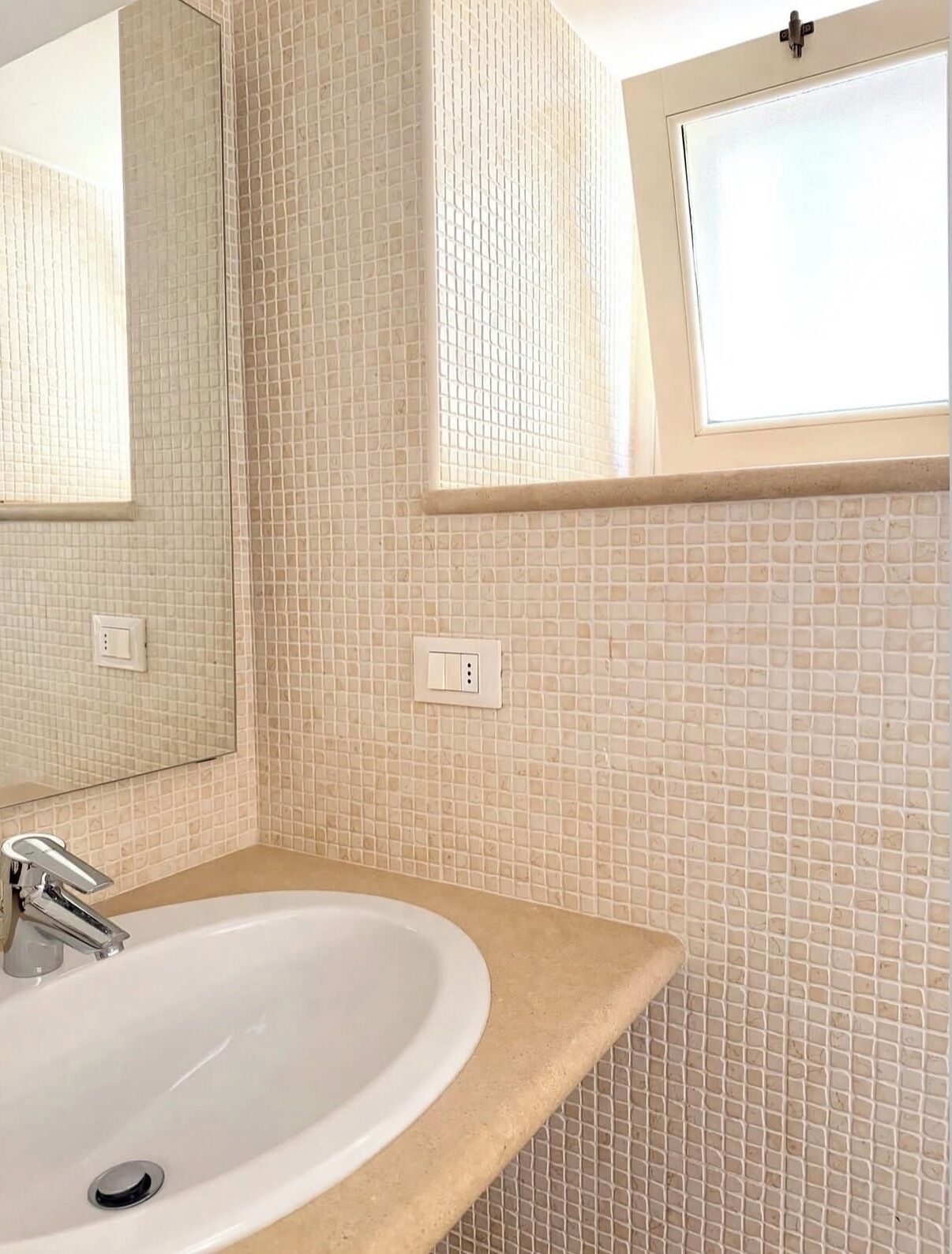A bathroom with a white sink, a mirror, and a tiled wall.