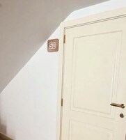A white door with a brass handle and a small wooden plaque with the number '51' on the wall above it.