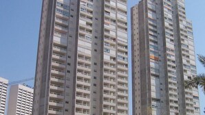 Korkea asuinkerrostalo, jossa on useita parvekkeita ja kirkas taivas.