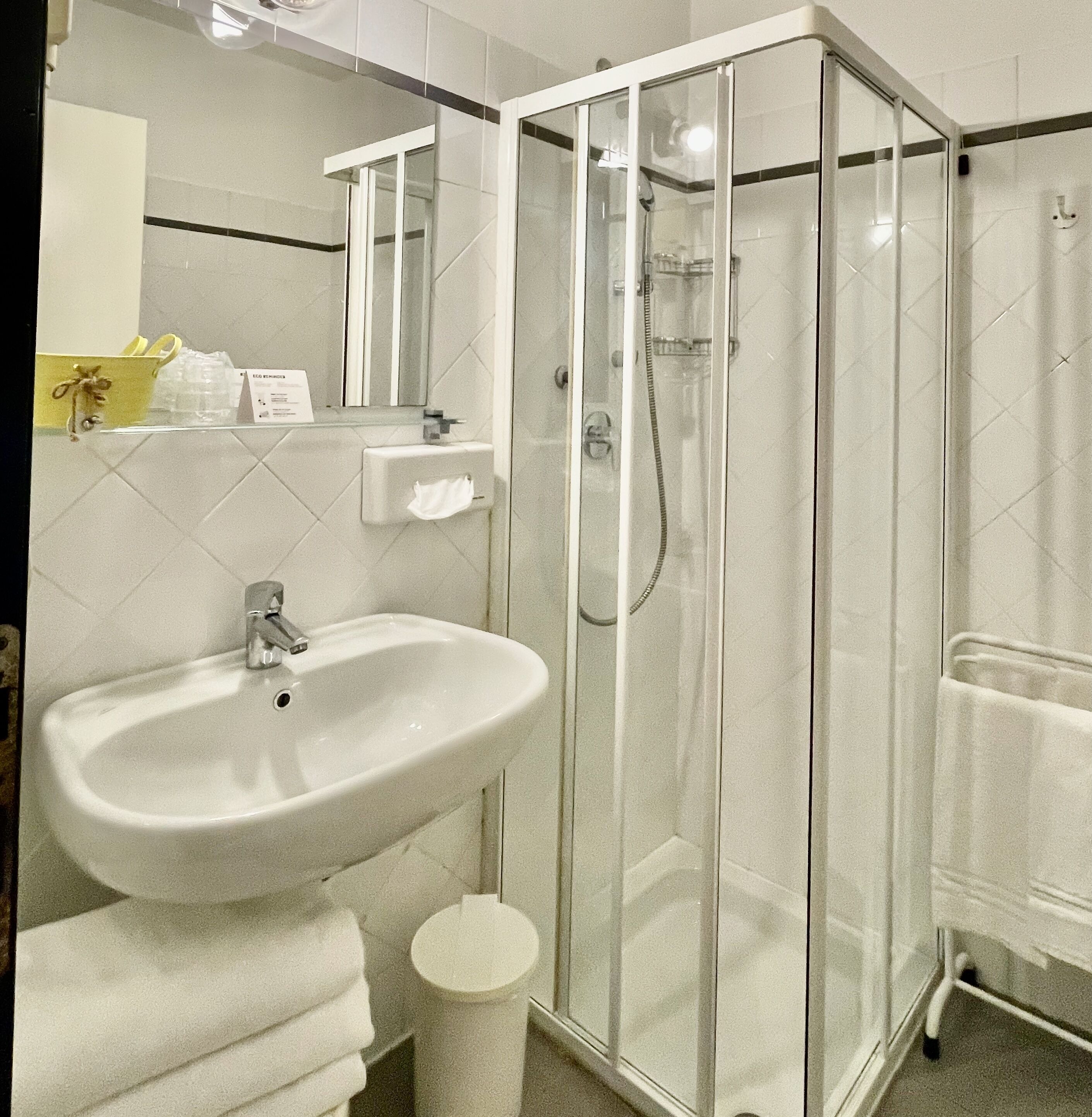 Un baño moderno con ducha envuelta en vidrio, un lavamanos y un espejo.