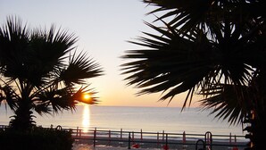 A sunset view with palm trees and a beach in the background.