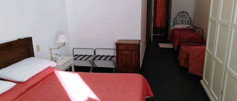 A hotel room with a bed, a desk, two chairs, a small cabinet, and a wardrobe.