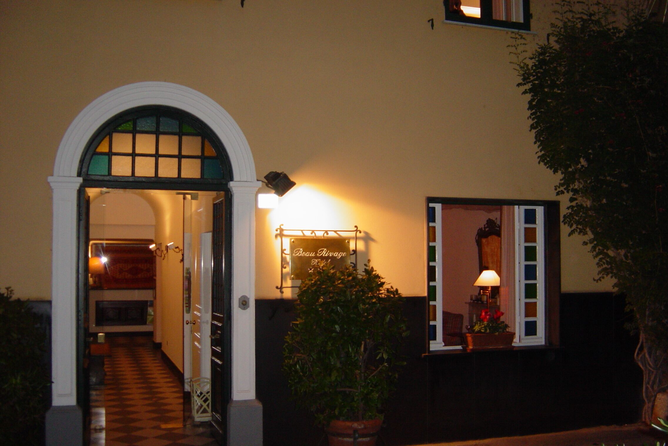 Una entrada con un arco blanco, un cartel que dice "Beau Rivage" y una planta en maceta.