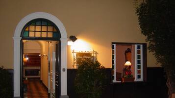 Uma entrada com arco branco, uma placa com a inscrição "Beau Rivage" e um vaso de planta.