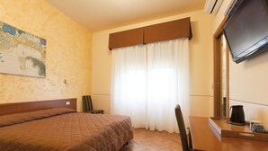 A hotel room with a large bed, a desk with a coffee maker, a chair, a television, and a window with curtains. - Maison de Charme (Florence)