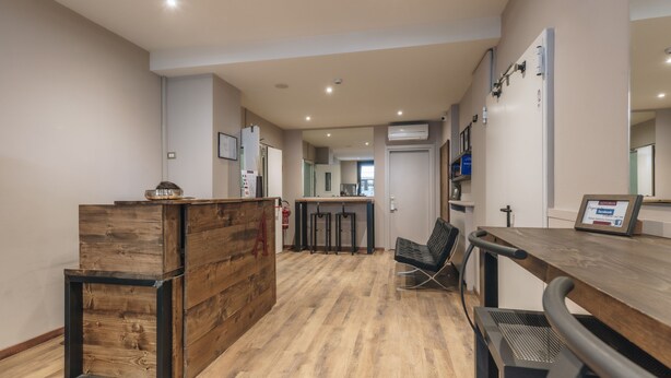 A modern kitchen with wooden cabinetry, a central island, and a seating area with a bar stool. - Hotel Astoria (Cremona)