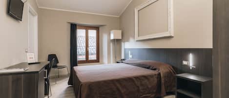 Habitación de hotel con cama, escritorio, silla y televisor.