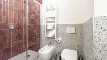 Une salle de bain équipée d’une douche, d’un bidet, de toilettes et d’un porte-serviettes.