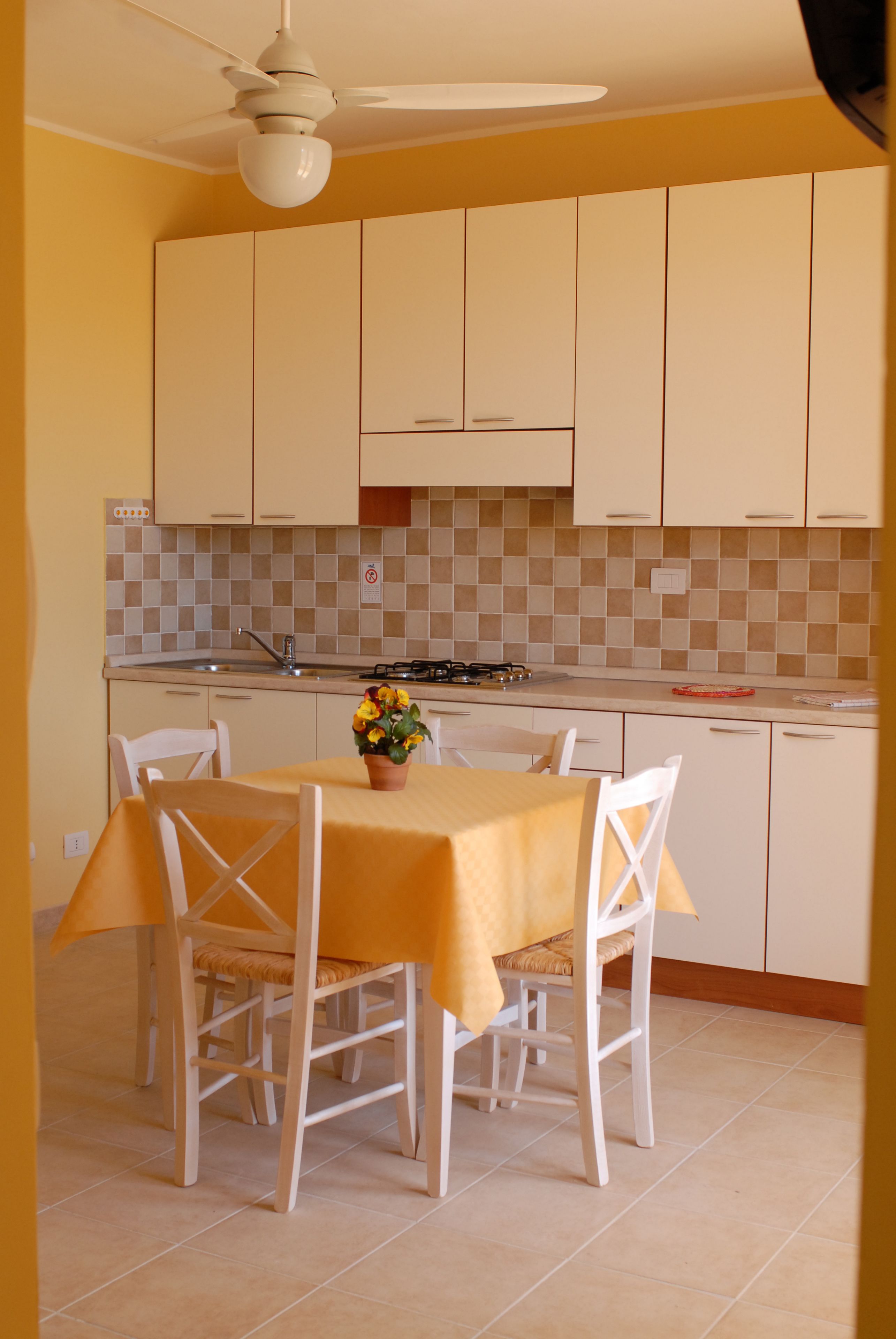 Une cuisine avec des meubles blancs, un pare-feu en carrelage et une table à manger avec des chaises.