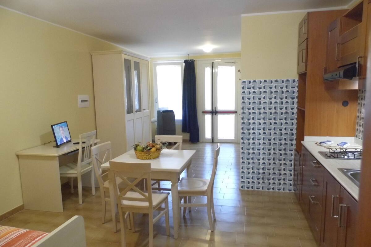 Cocina compacta con comedor, televisor sobre un escritorio y pared con diseño.
