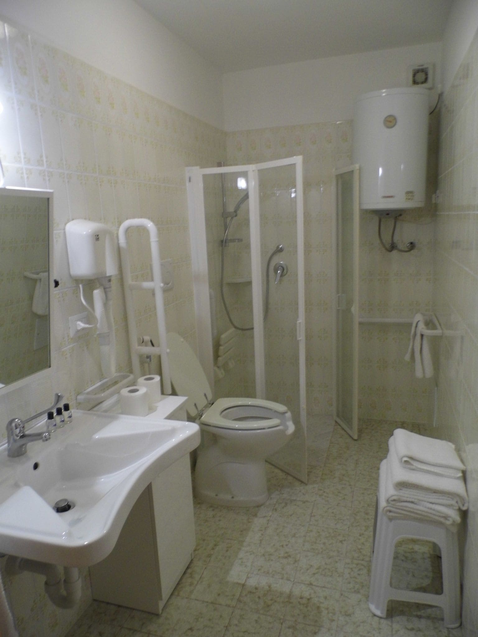 Une salle de bain équipée de toilettes, d’un lavabo, d’une douche et d’un porte-rouleau de papier toilette.